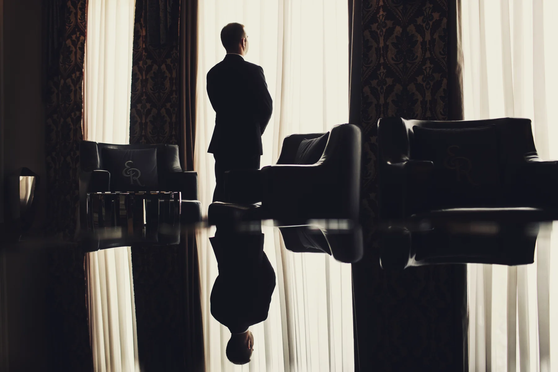 An executive standing in reflection beside the windows of a private meeting room
